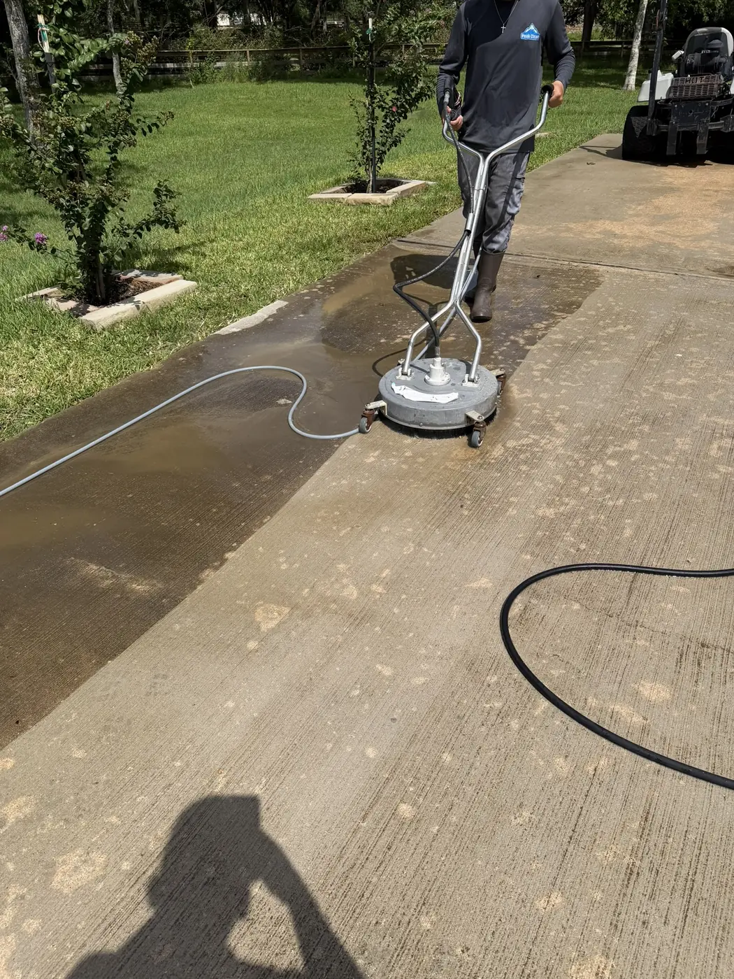 Technician using a surface cleaner attachment on a driveway in Houston, TX