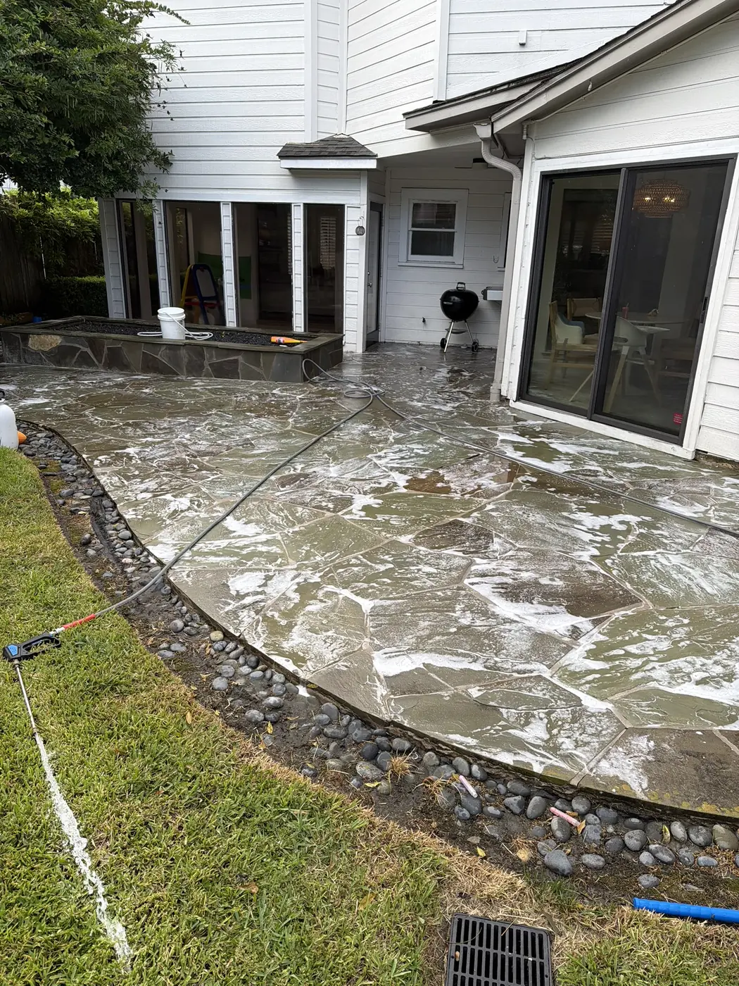 Flagstone patio being pressure washed with cleaning solution in Houston, TX