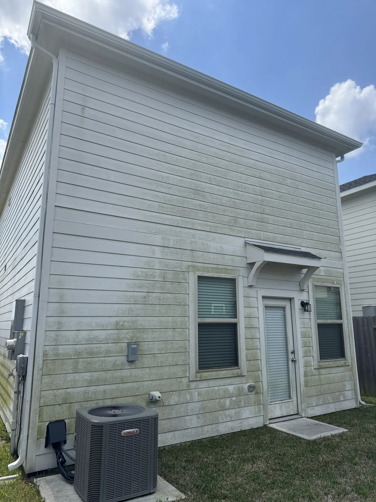 Algae-streaked vinyl siding on a Houston, TX home before soft washing