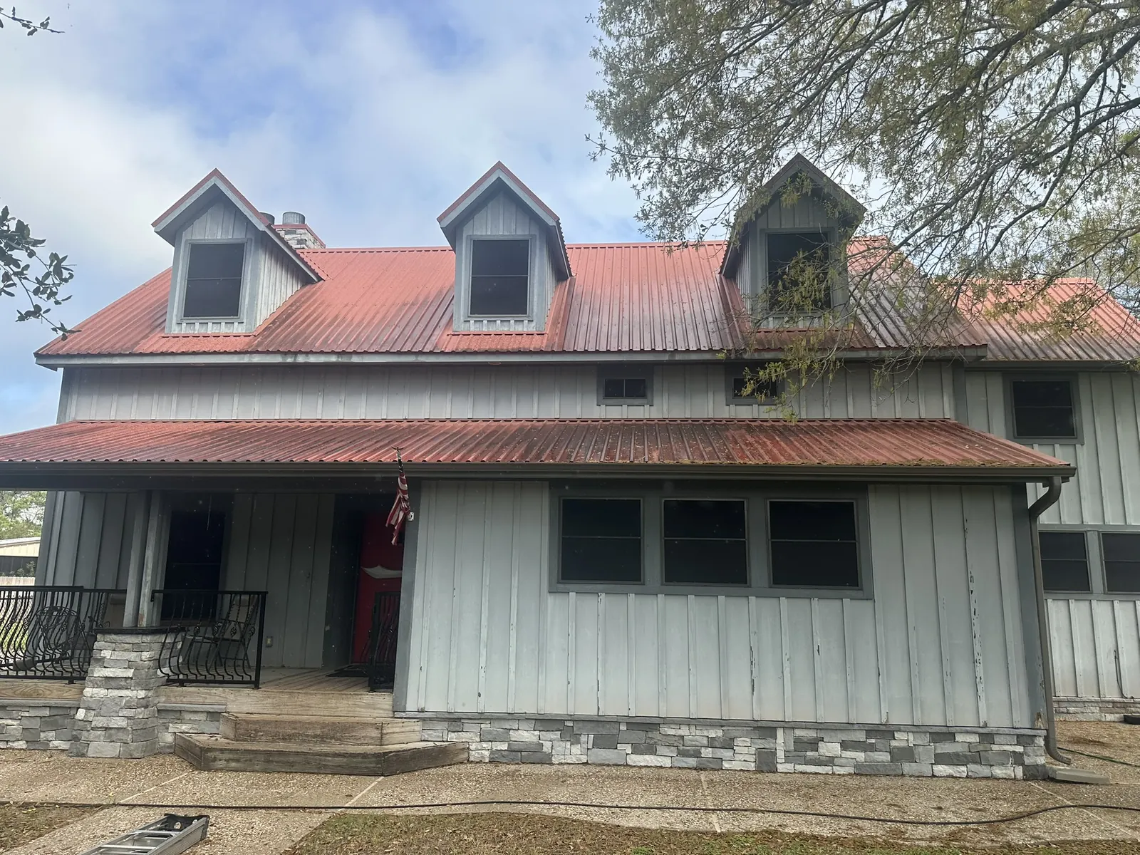 Rust-streaked, moss-stained metal roof on a Houston, TX home before cleaning