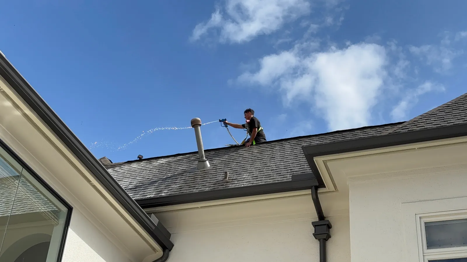 Technician soft washing a roof vent in Houston, TX
